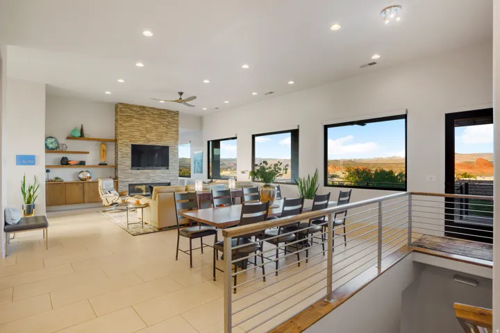 Open-concept living area with a stone-clad fireplace, integrated shelving, and large windows