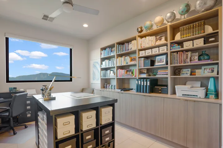 Built-in shelving with integrated cabinetry, recessed lighting, ceiling fan, and a wide window