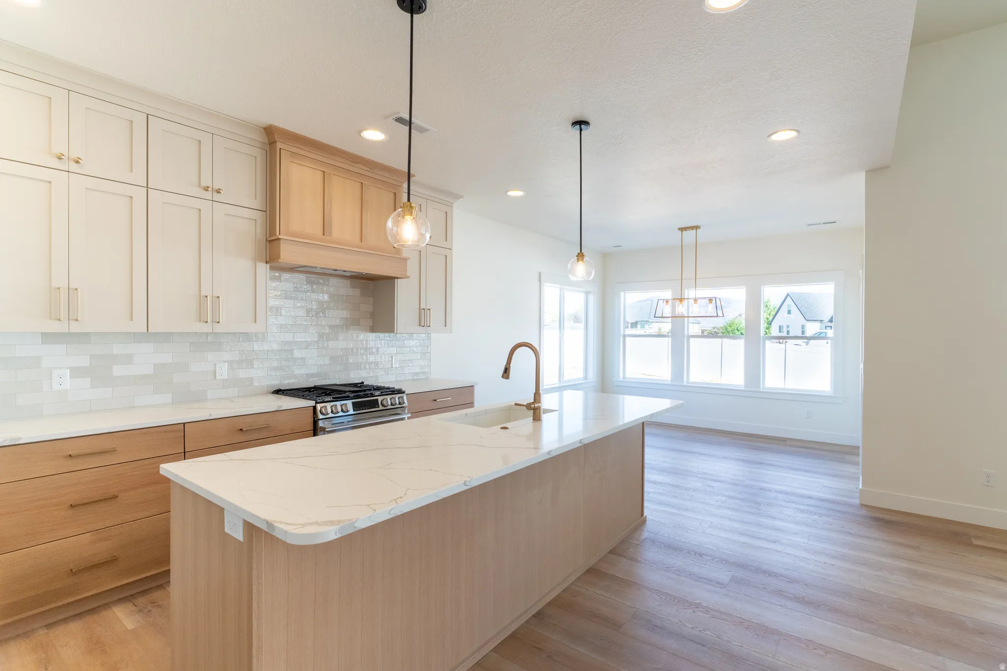 Kitchen featuring two-tone cabinetry, a substantial kitchen island with a built-in sink, and a tile backsplash