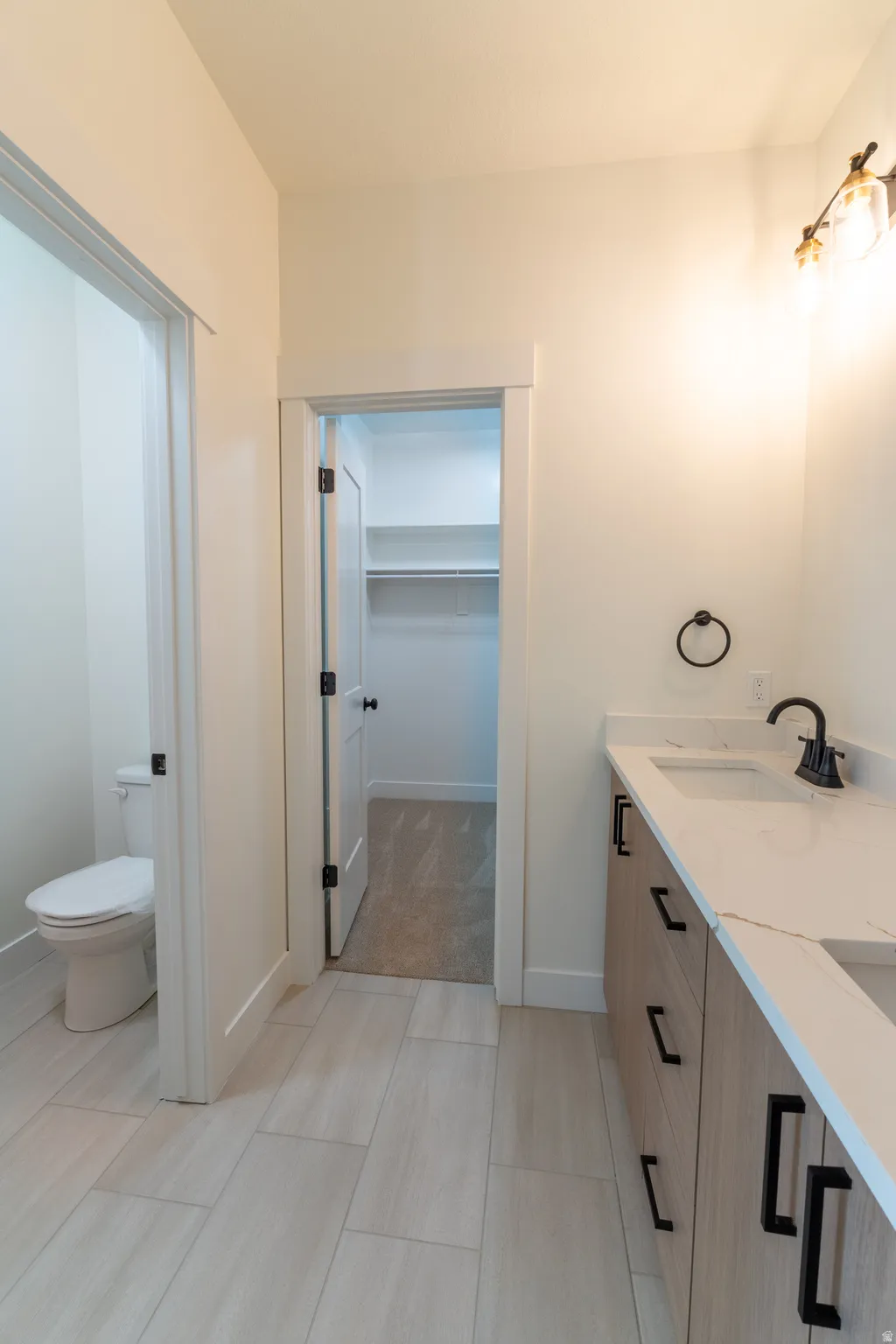 Dual vanity with stone-look countertop, wood-finish cabinetry, and matte black hardware