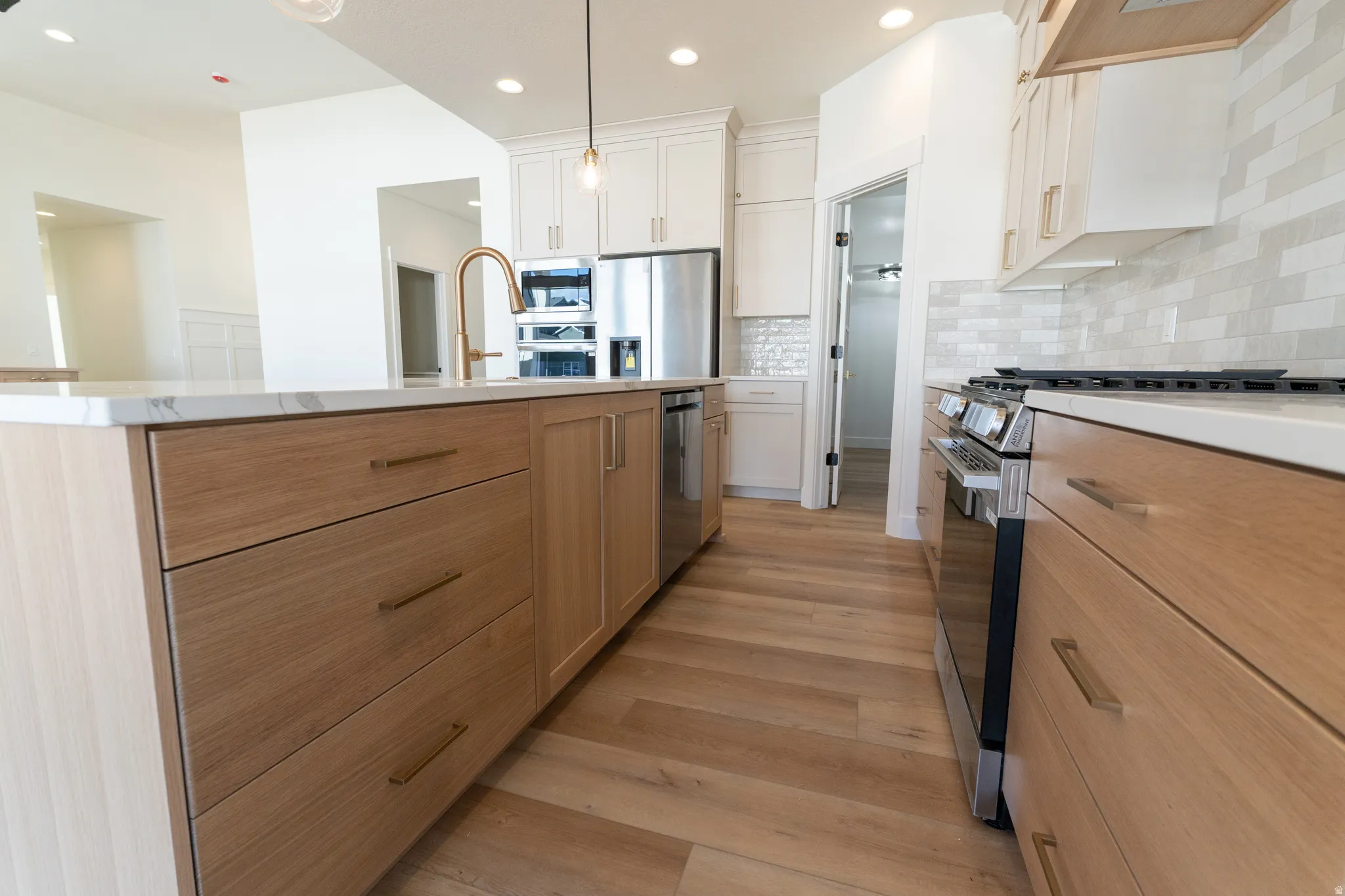 Spacious kitchen featuring a large island with a countertop, wood-finish cabinetry, stainless steel appliances, and wood-finish flooring