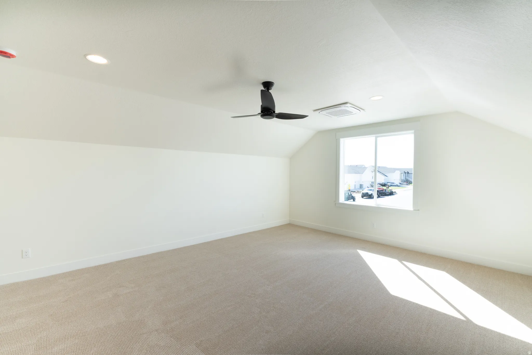 Vaulted ceiling, recessed lighting, ceiling fan, expansive window, and neutral . carpeting. upstairs loft for extra living space.