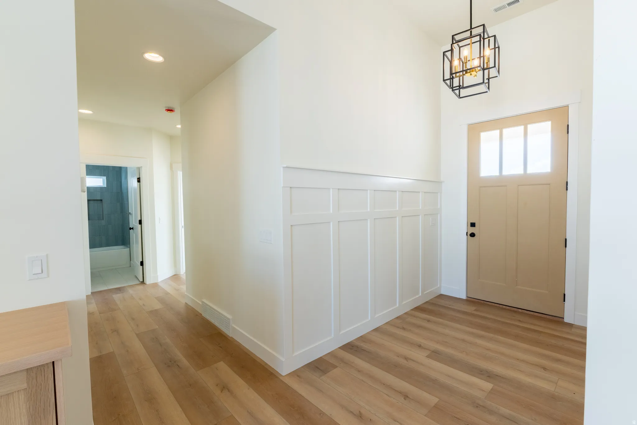 Entryway featuring wood-finish flooring, wainscoting, recessed lighting, and a modern geometric pendant light