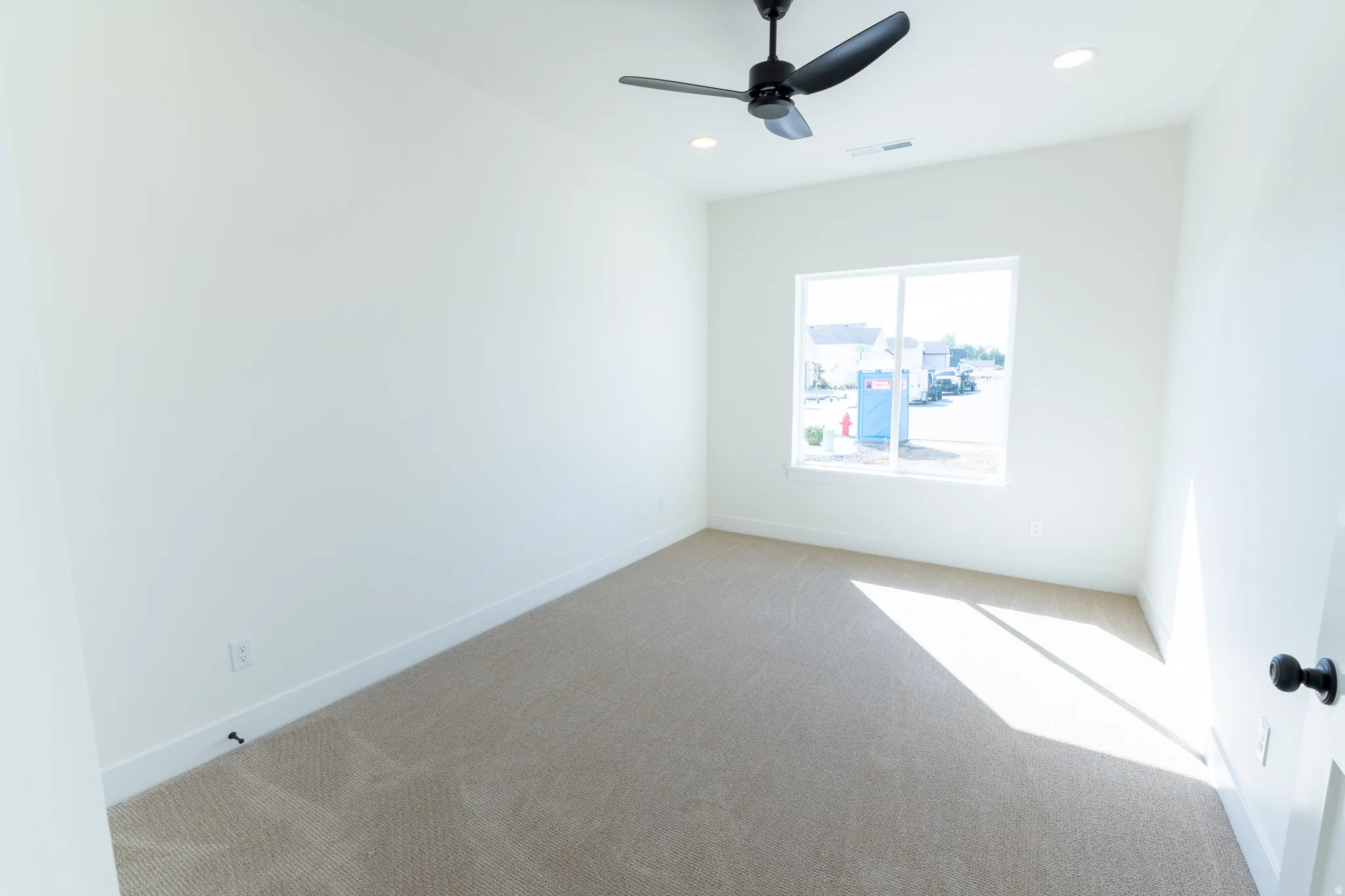 Recessed lighting, ceiling fan, neutral carpet, white walls, and a white window frame