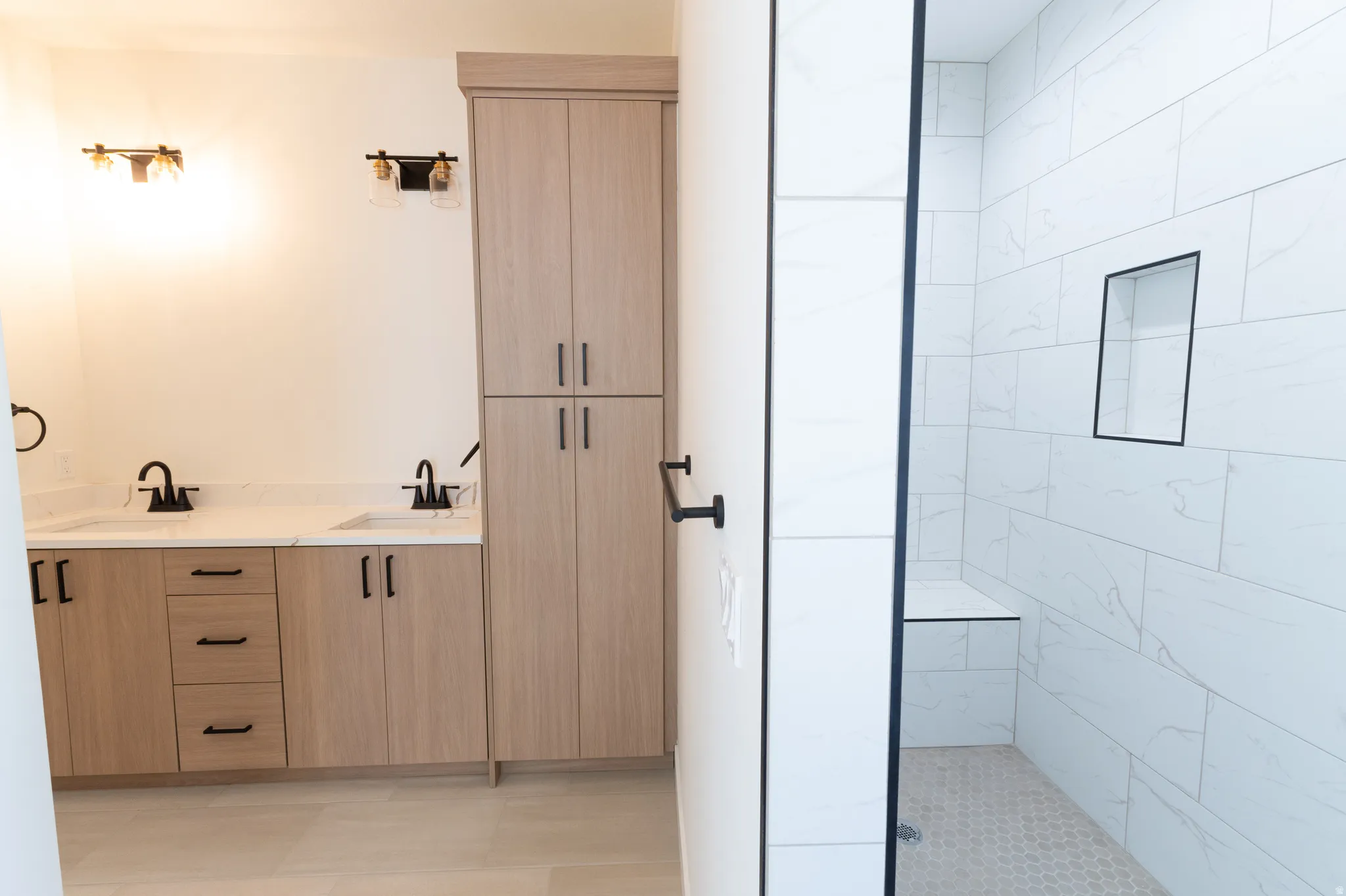 Dual vanity with wood-finish cabinetry, white countertop, and matte black fixtures