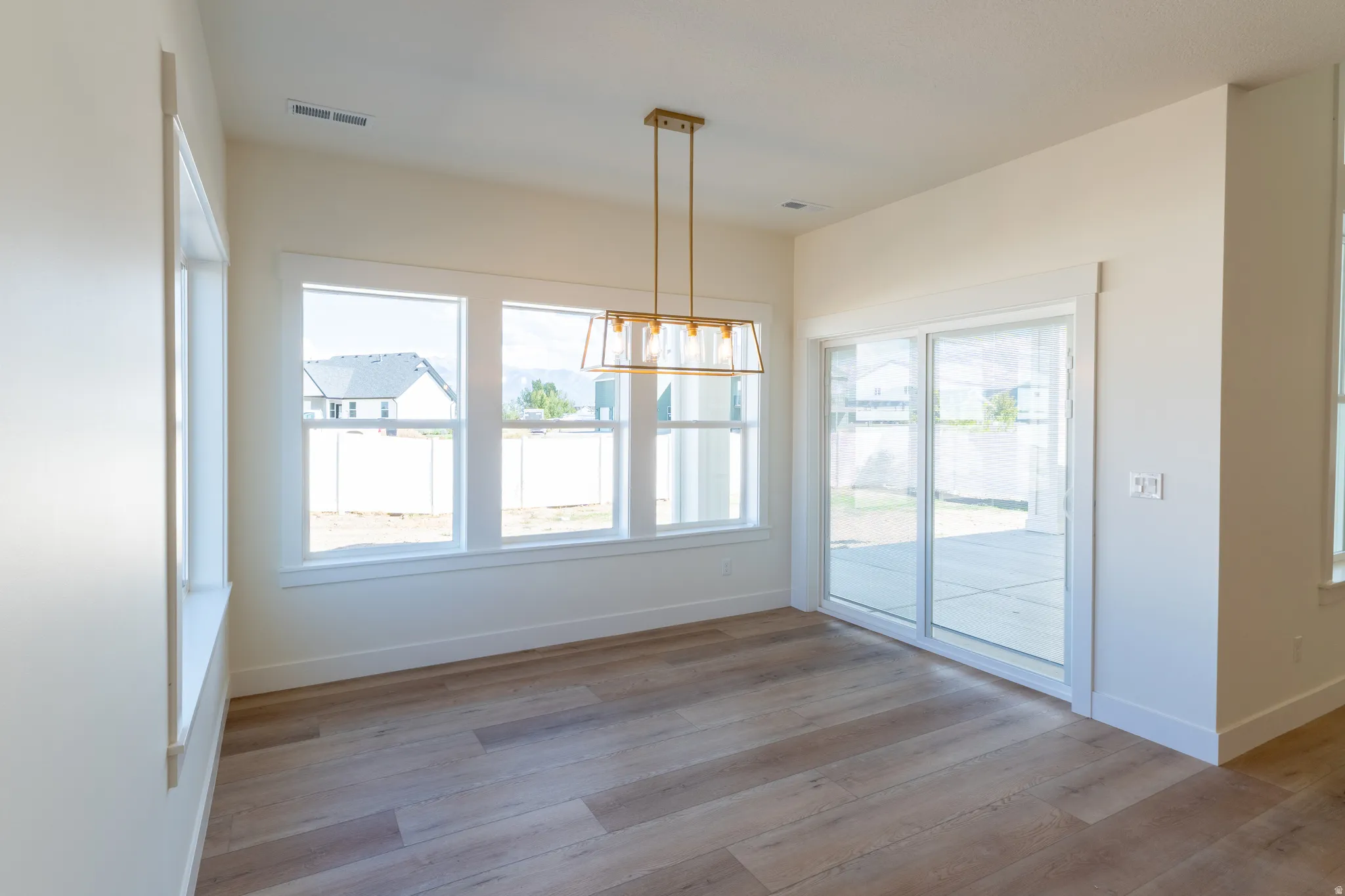 Spacious interior with wood-finish flooring, multiple large windows, and a sliding glass door