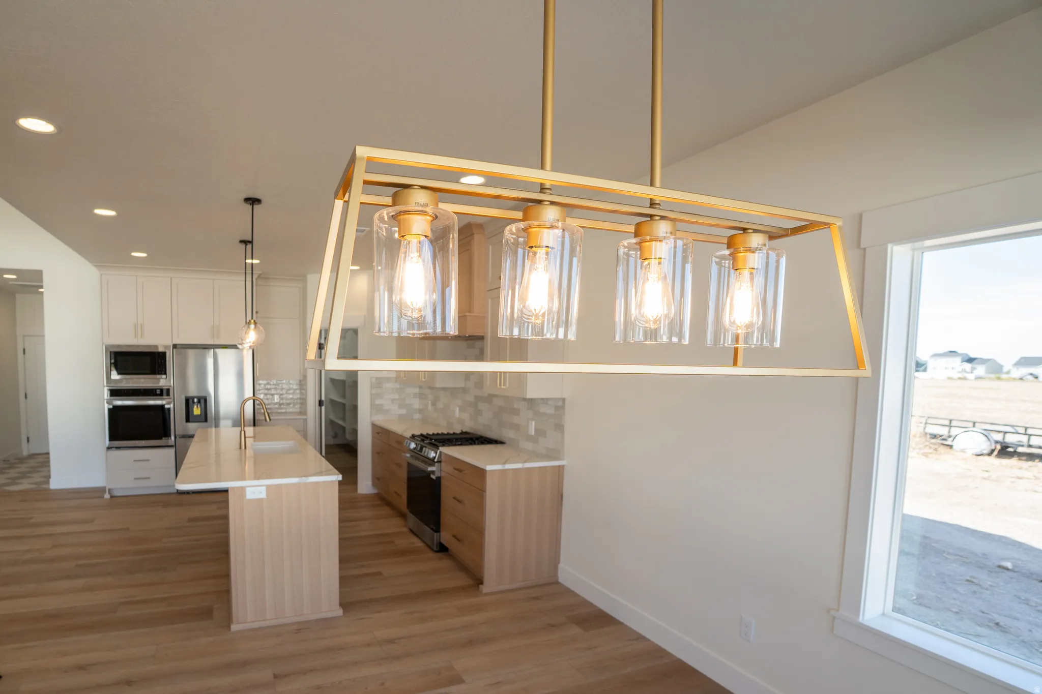 Gourmet kitchen featuring a center island with sink, stainless steel appliances, and wood-finish flooring