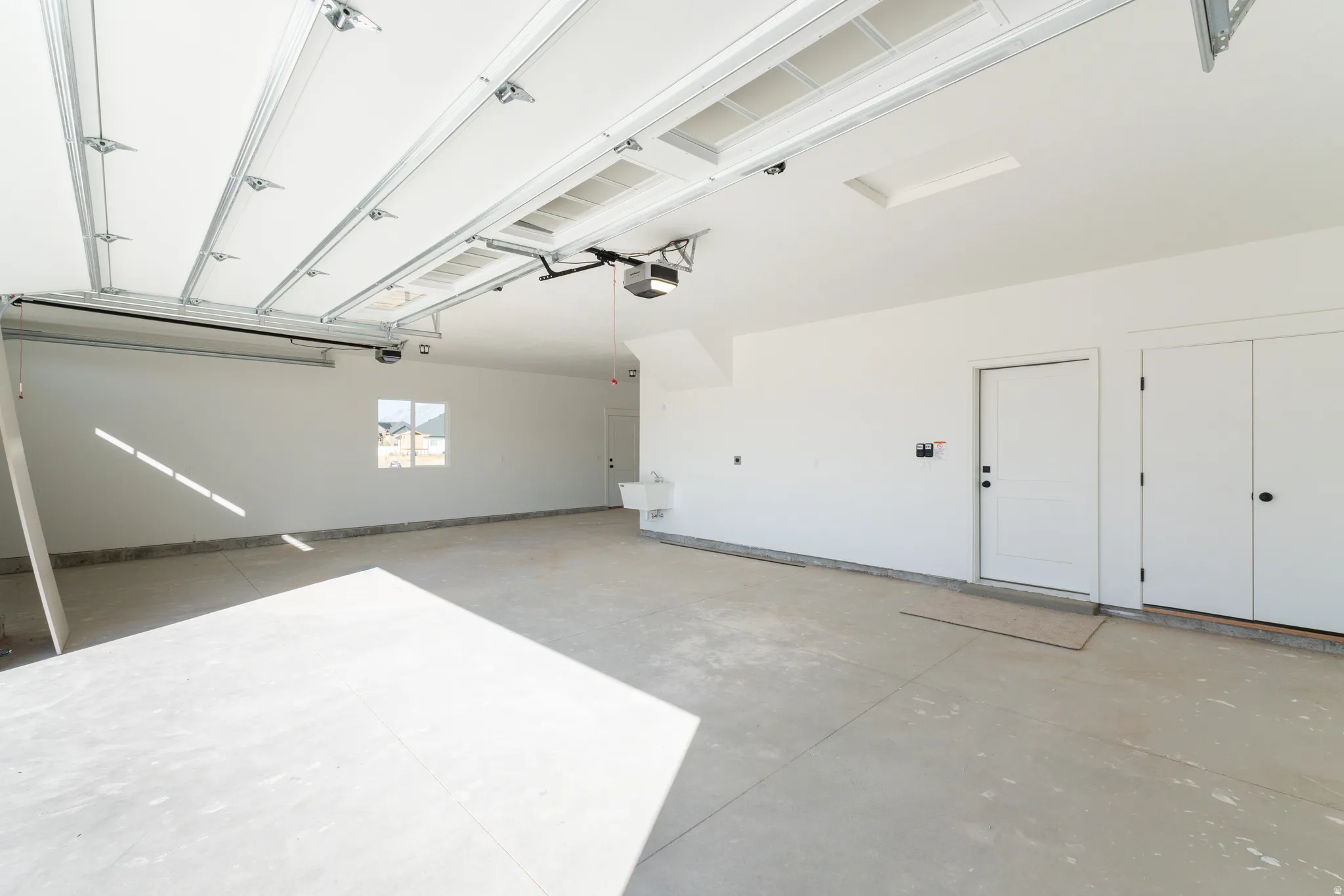 Spacious garage featuring a concrete floor, bright white walls, and a utility sink