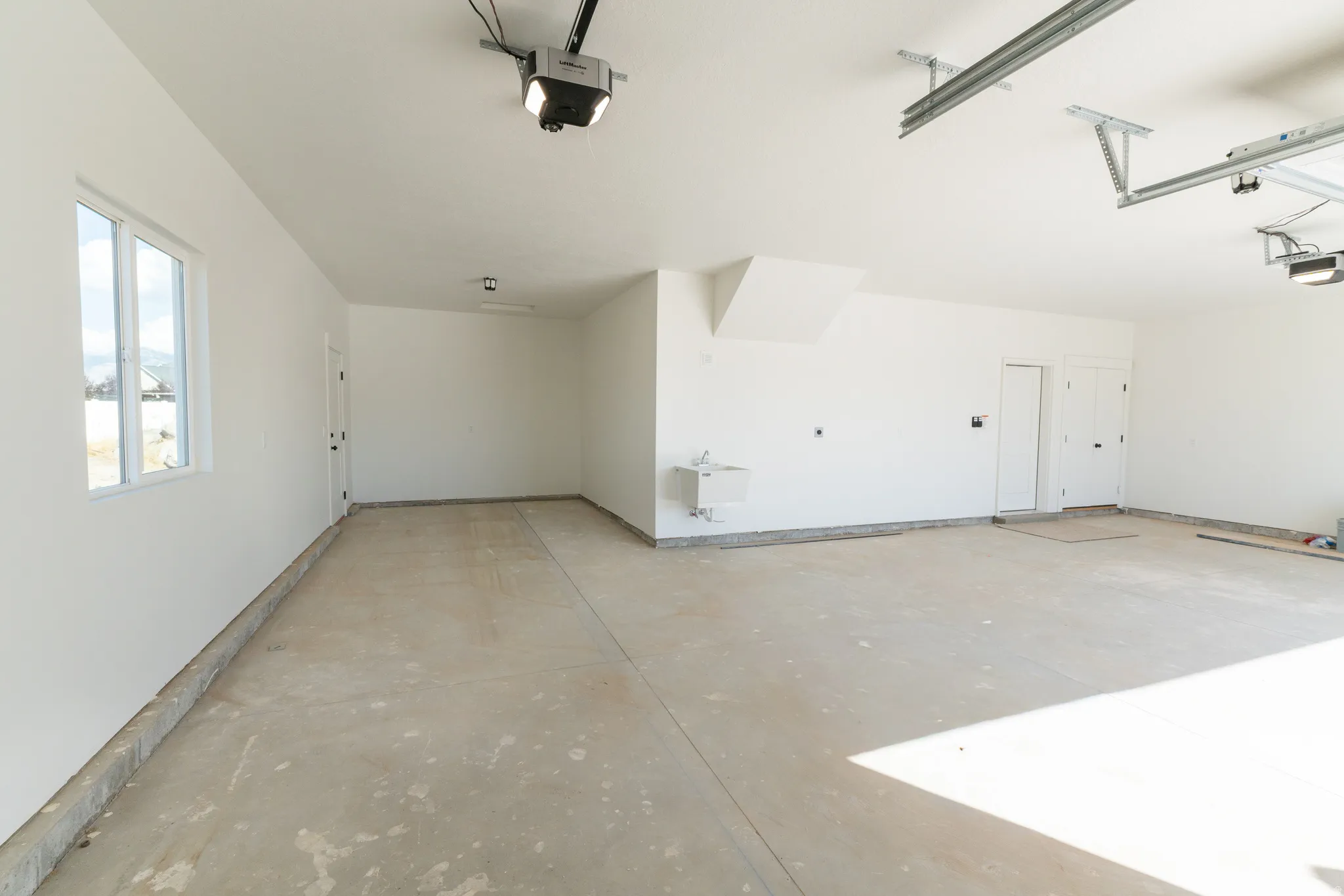 Spacious garage with concrete flooring, white painted walls, and overhead lighting
