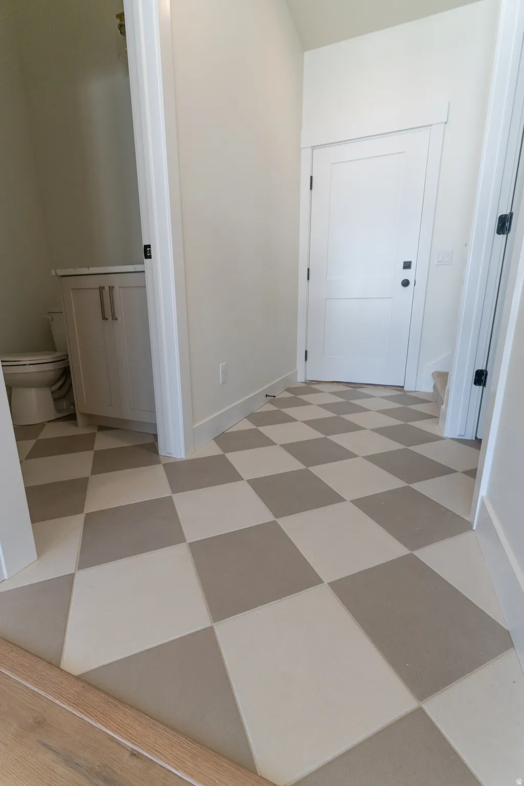 Checkerboard tile flooring, white interior doors, light gray wall paint, and a built-in vanity with white countertop