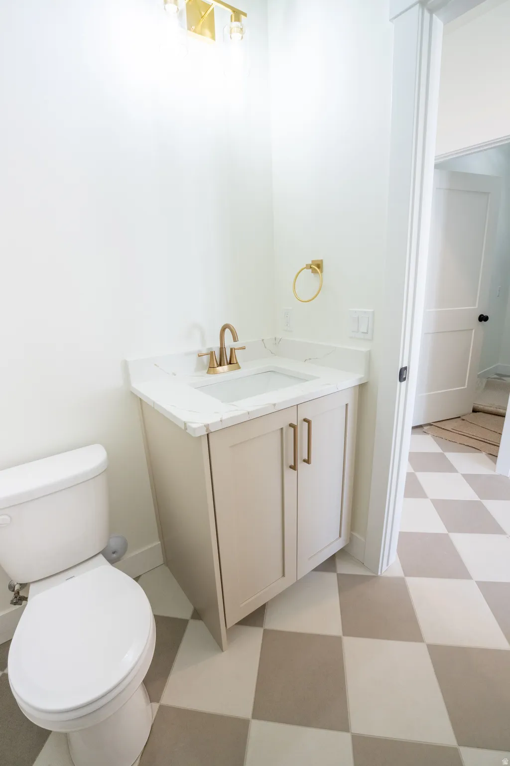 Vanity with stone-finish countertop, under-mount sink, and gold-finish fixtures