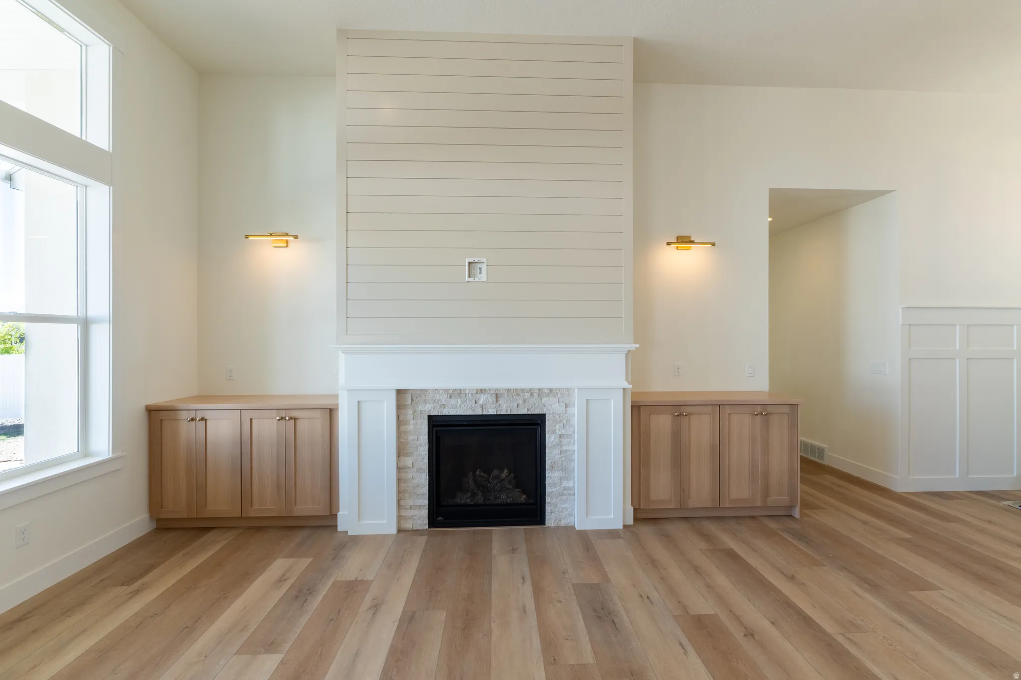 Fireplace with stone surround and shiplap detailing, complemented by built-in wood cabinetry