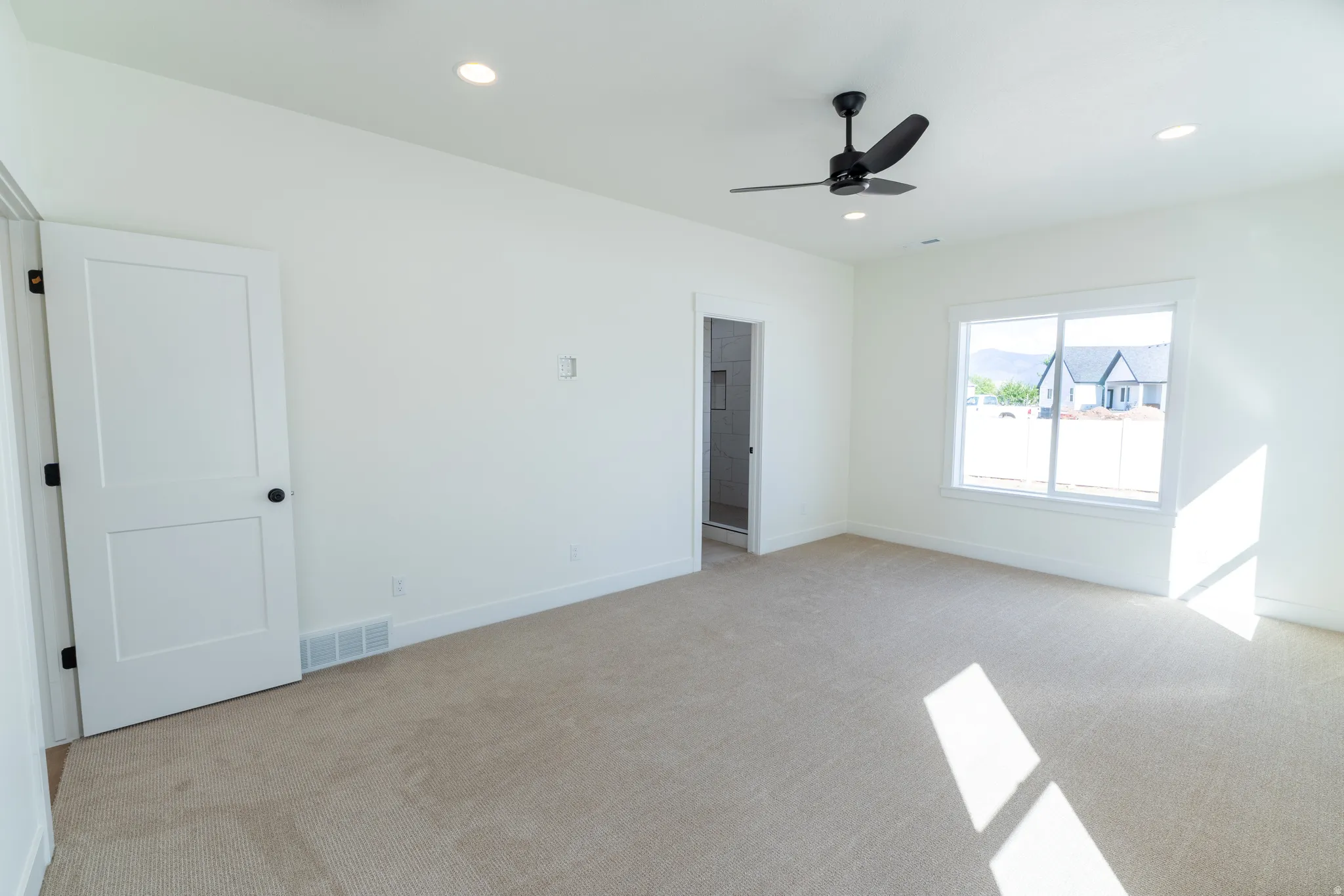 Recessed lighting, neutral carpeting, white interior doors with black hardware, modern ceiling fan, and large window. Master Bedroom