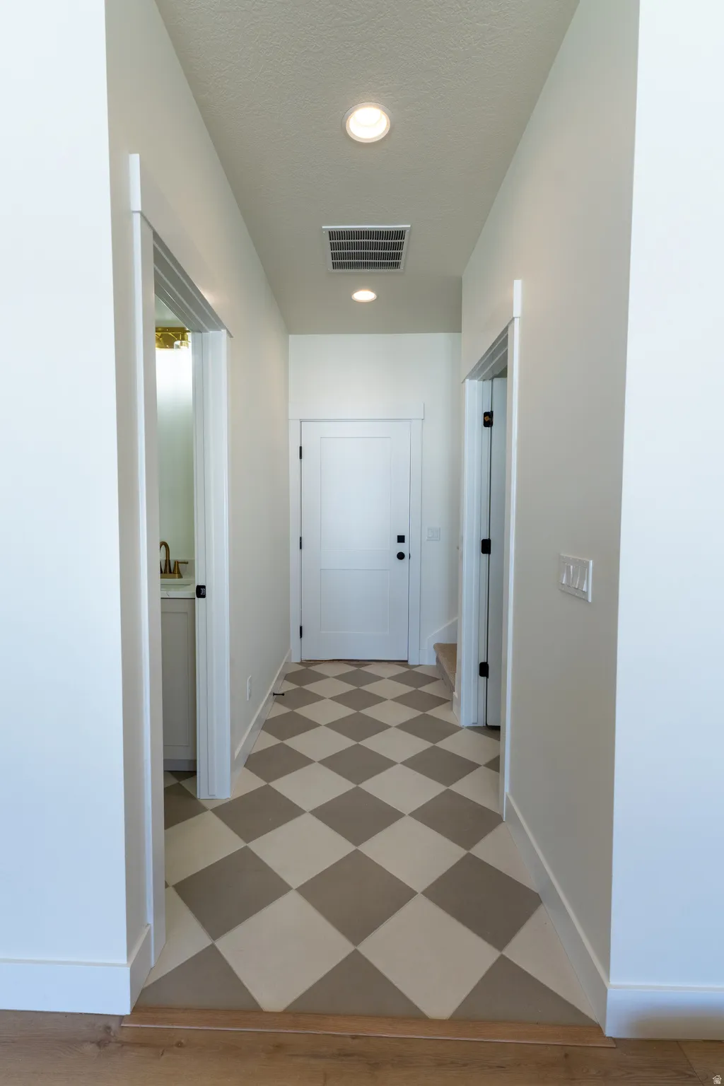 Hallway with checkerboard flooring, recessed lighting, and white paneled doors