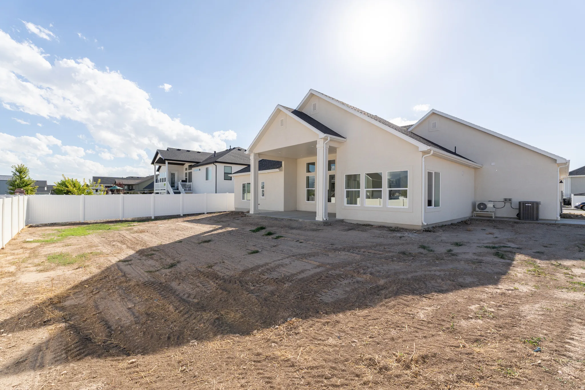 White stucco exterior with a covered patio and multiple large windows