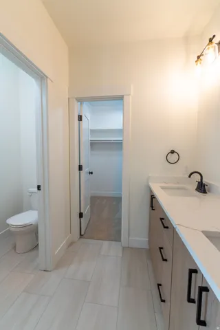 Dual vanity with stone-look countertop, wood-finish cabinetry, and matte black hardware