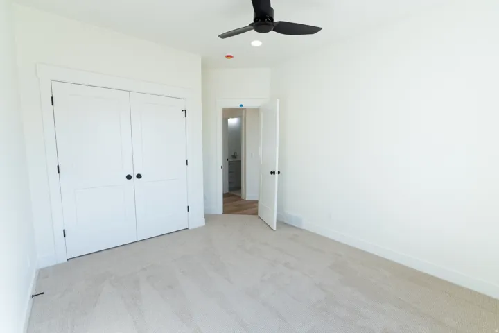 Neutral tone wall finishes, soft carpet flooring, black ceiling fan, recessed lighting, and a double-door closet