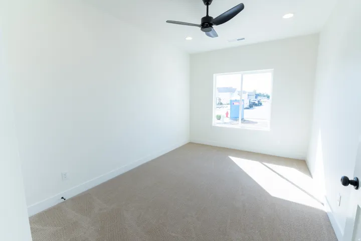 Recessed lighting, ceiling fan, neutral carpet, white walls, and a white window frame