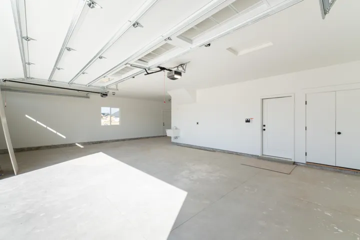 Spacious garage featuring a concrete floor, bright white walls, and a utility sink