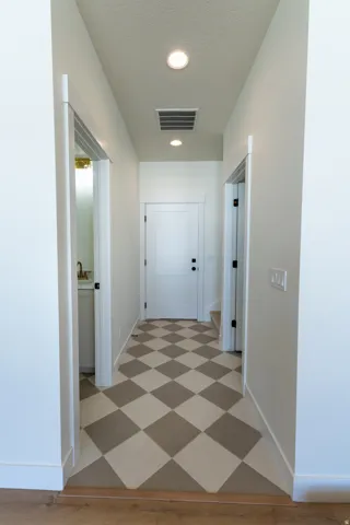 Hallway with checkerboard flooring, recessed lighting, and white paneled doors