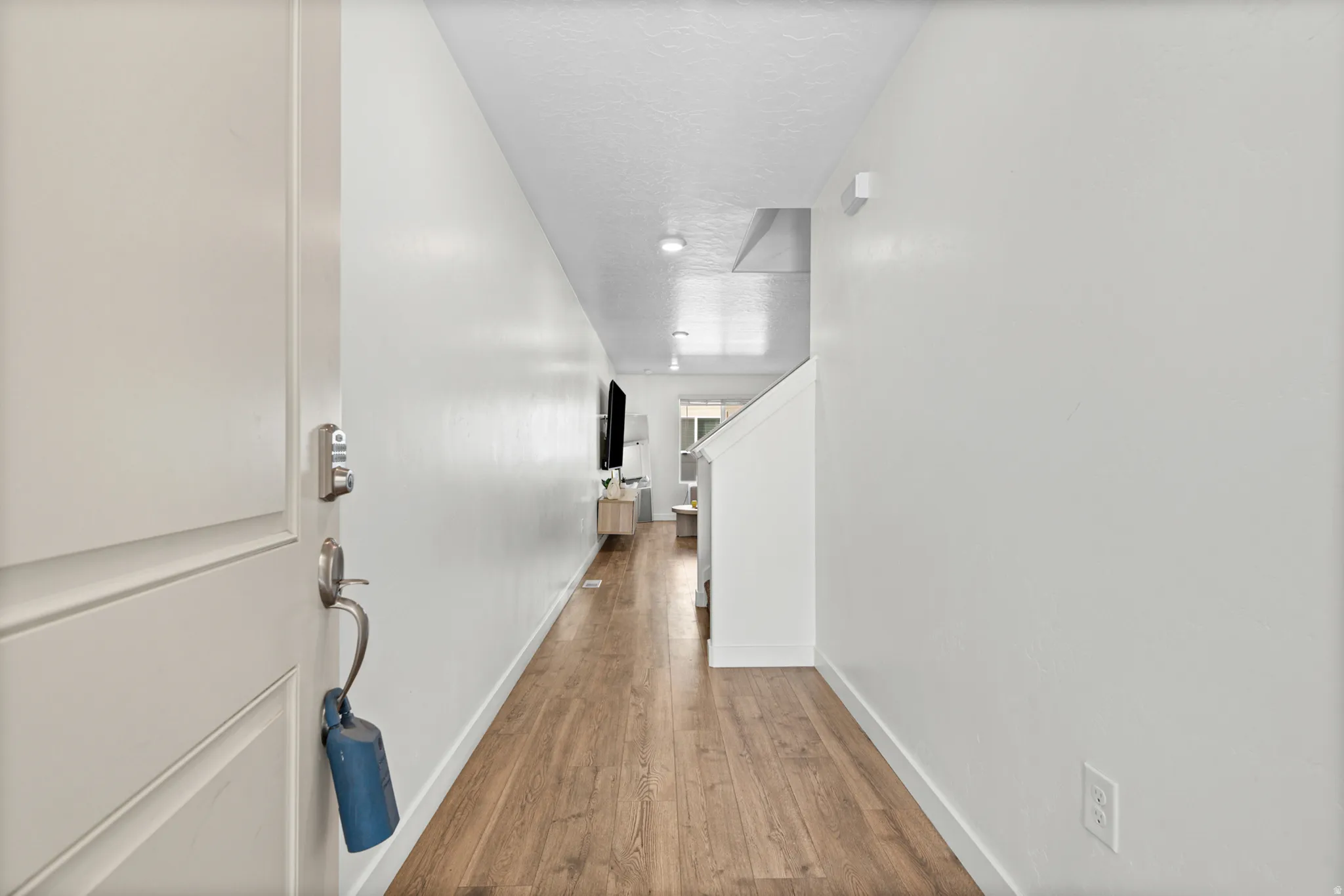 Wood-finish flooring throughout, white painted walls, and recessed lighting fixtures