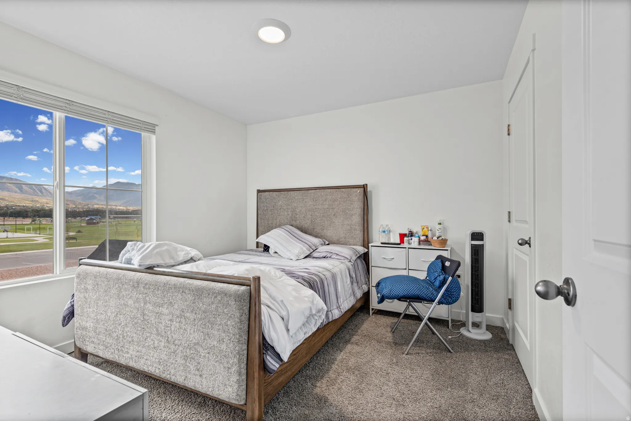 Recessed lighting, large window with blinds, mountain scenery, light gray wall paint, and gray carpeting