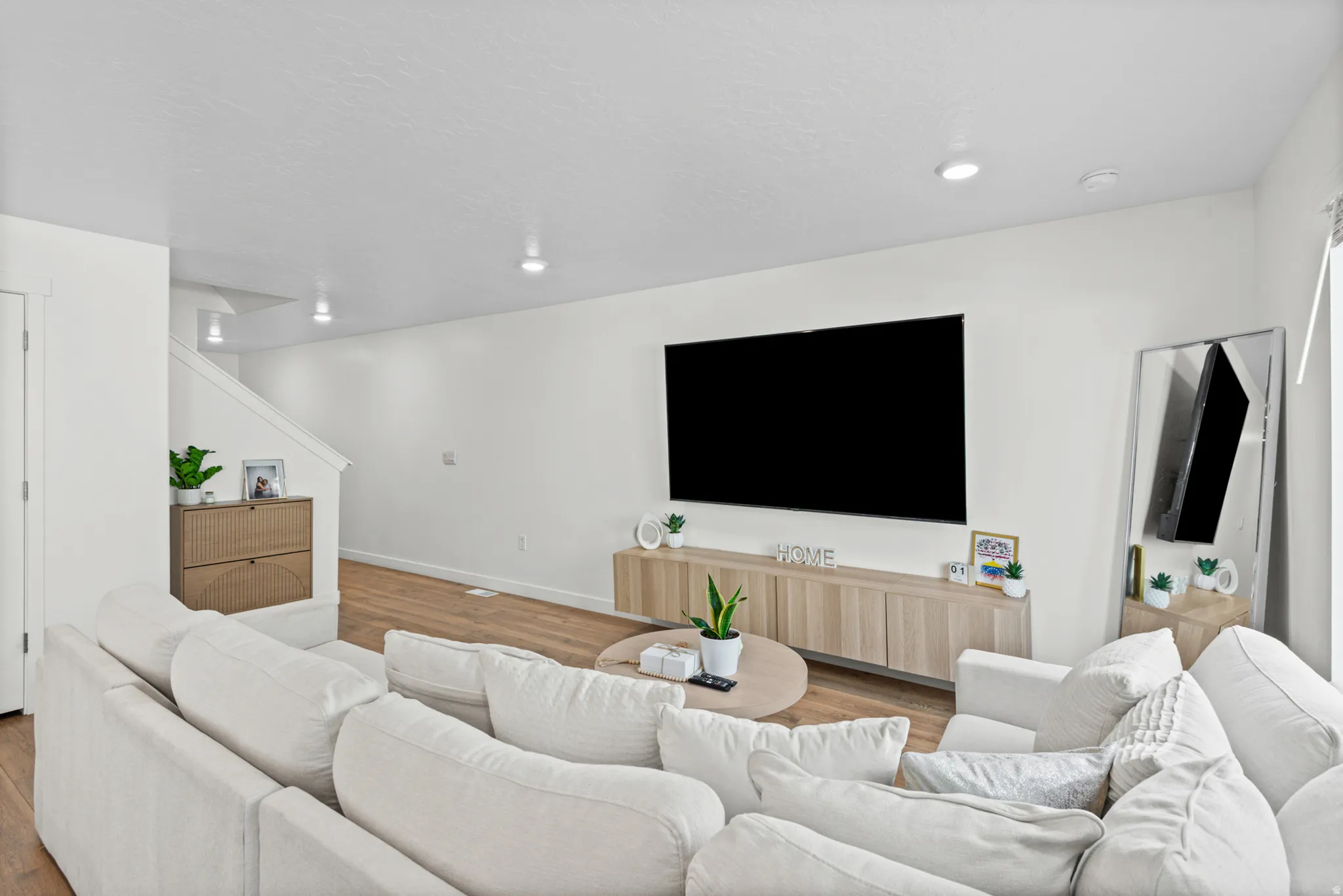Recessed lighting, wood-finish flooring, white walls, and an open staircase