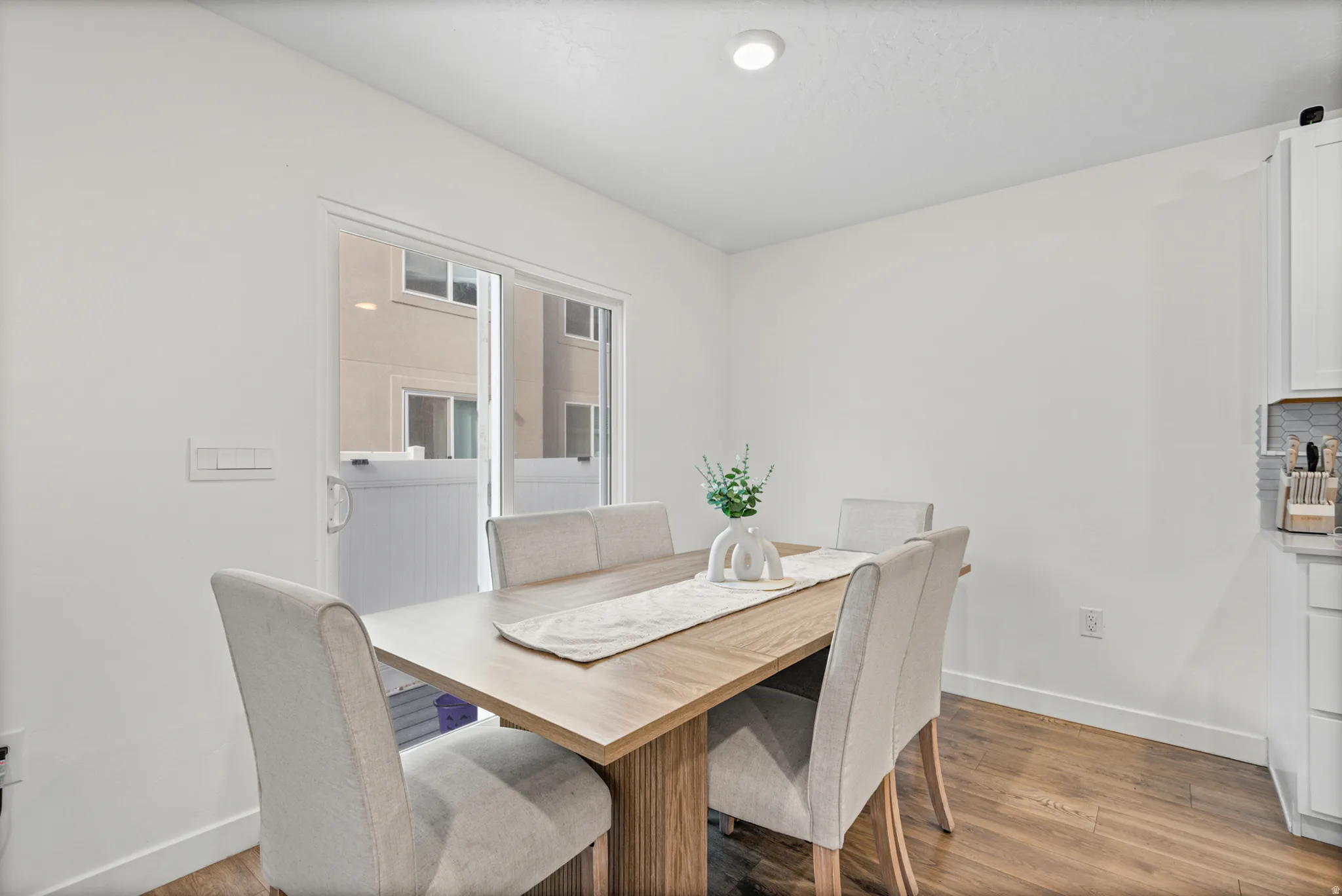 Recessed ceiling lighting, wood-finish flooring, white walls, and a sliding glass door