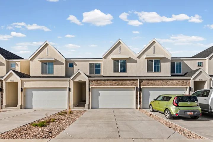 Stucco exterior with brick accents, attached garages, paved driveways, and peaked rooflines