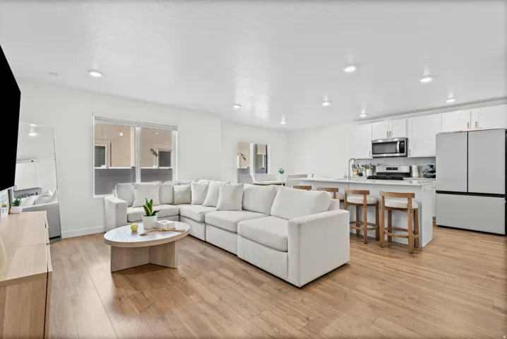Spacious open-concept living area with wood-finish flooring, recessed lighting, and a kitchen island with seating