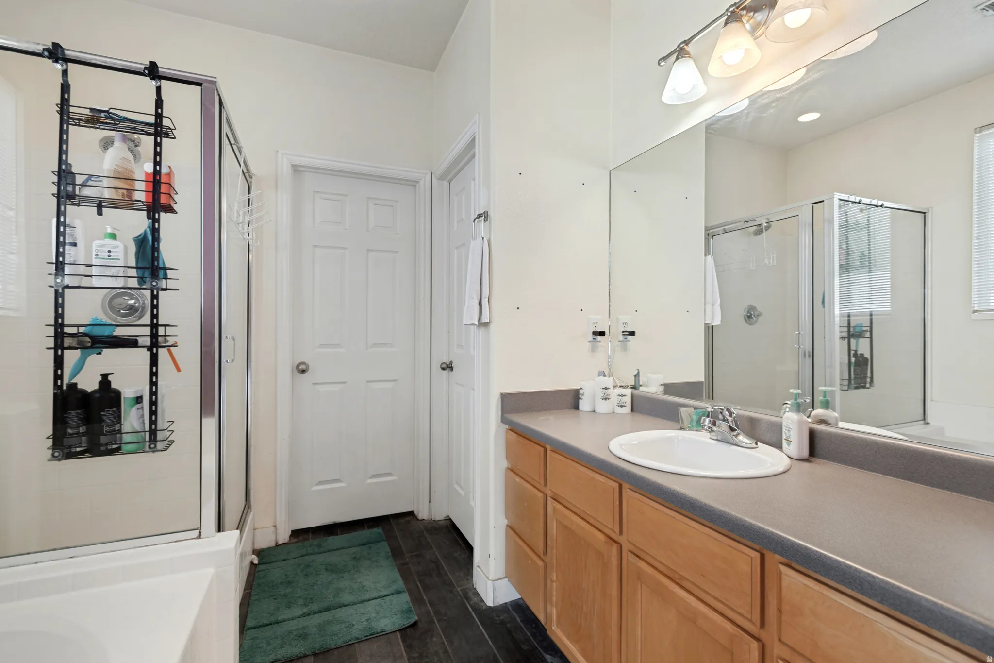 Dual-sink vanity with ample counter space, large wall-mounted mirror, and glass-enclosed shower