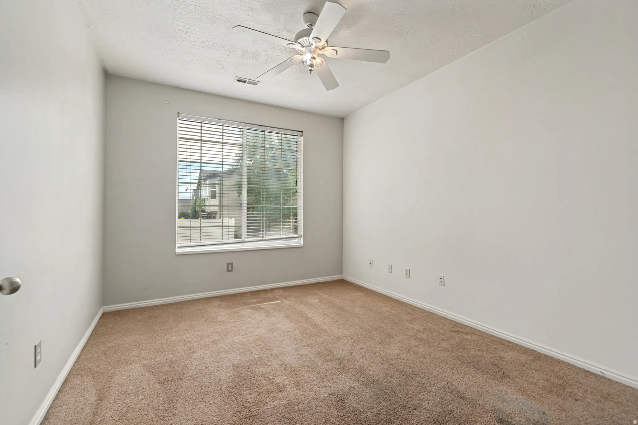 Carpeted flooring with a window featuring blinds, a white ceiling fan, and white walls