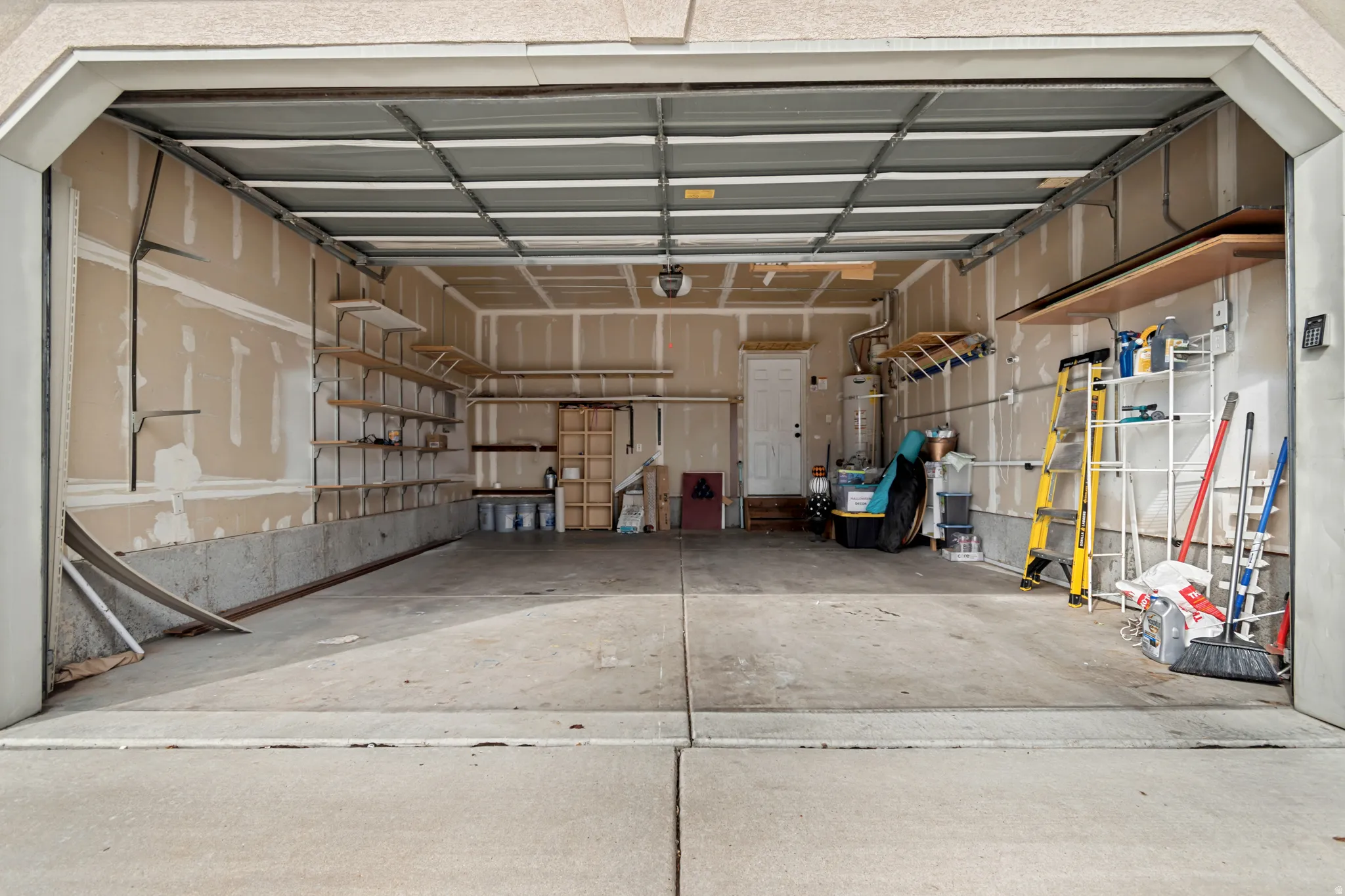 Attached garage with concrete flooring, exposed wall framing, and integrated shelving