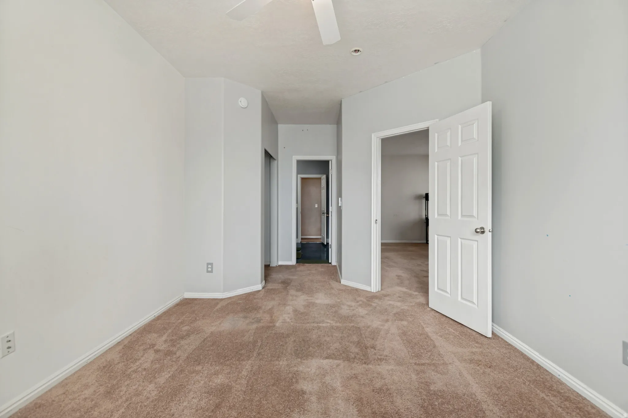 Neutral wall color, carpet flooring, interior panel door, ceiling fan