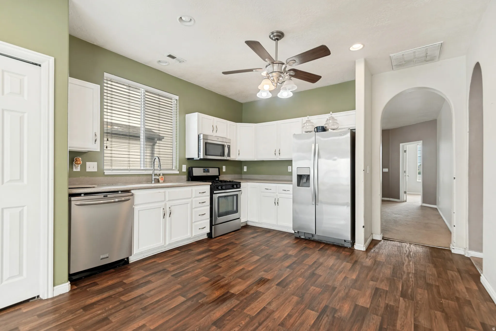 Kitchen featuring white cabinetry, stainless steel appliances, wood-finish flooring, and recessed lighting
