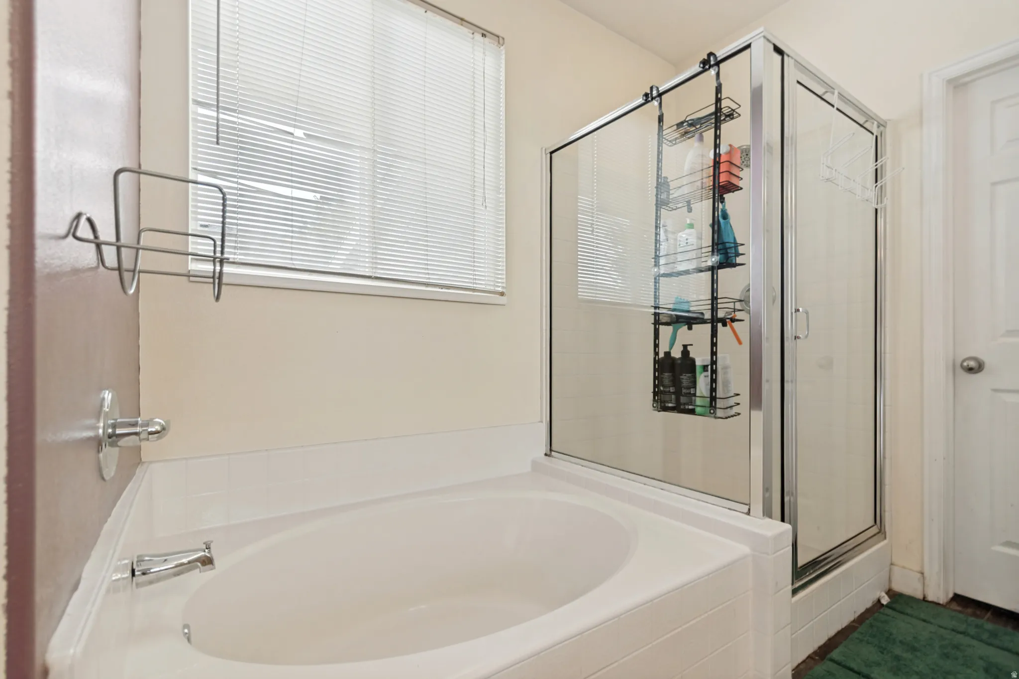 Built-in soaking tub with chrome fixtures, glass-enclosed shower, and a privacy window
