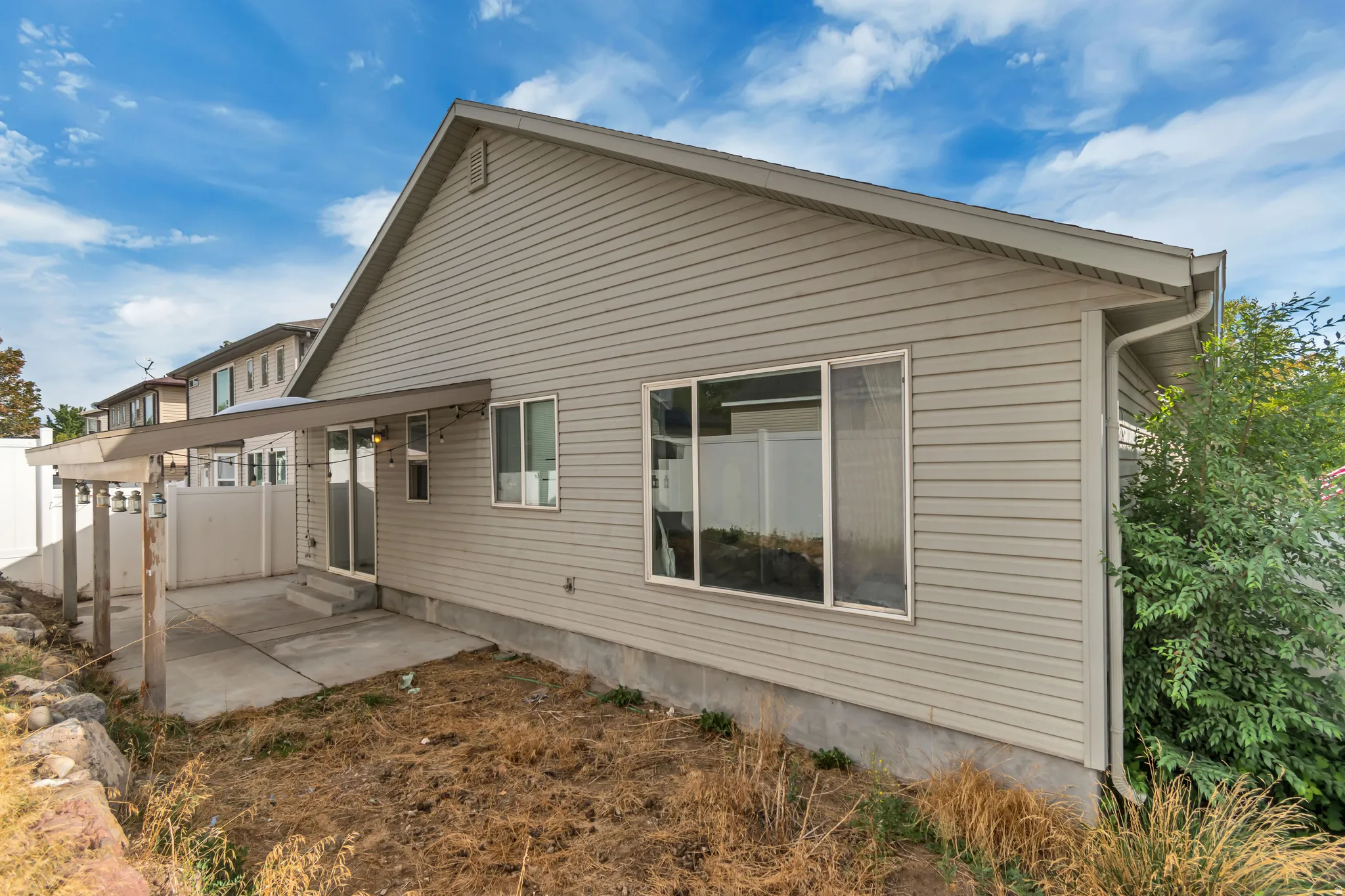 Rear exterior with neutral-toned horizontal siding, a covered patio, and a sliding glass door