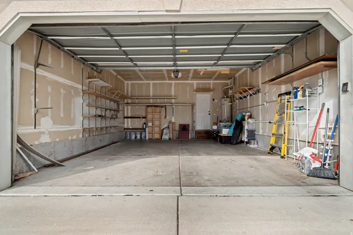 Attached garage with concrete flooring, exposed wall framing, and integrated shelving