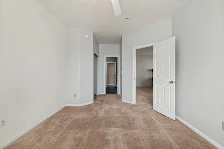 Neutral wall color, carpet flooring, interior panel door, ceiling fan