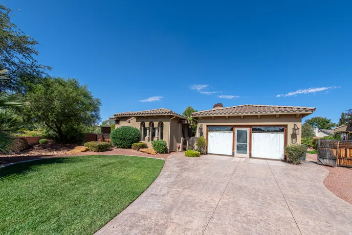 Stucco exterior with a tile roof, multi-arch window detail, and a stamped concrete driveway