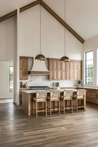 Vaulted ceiling with exposed wood beams, wood-finish flooring, custom wood cabinetry, stone countertop with integrated backsplash, and a central island
