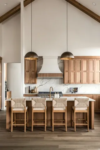Vaulted ceiling with exposed wood beams, light wood-finish cabinetry, white countertop island, marble-look slab backsplash, and wood-finish flooring