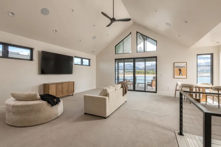 Vaulted ceiling, recessed lighting, black frame sliding glass doors, black frame windows, built-in ceiling fan