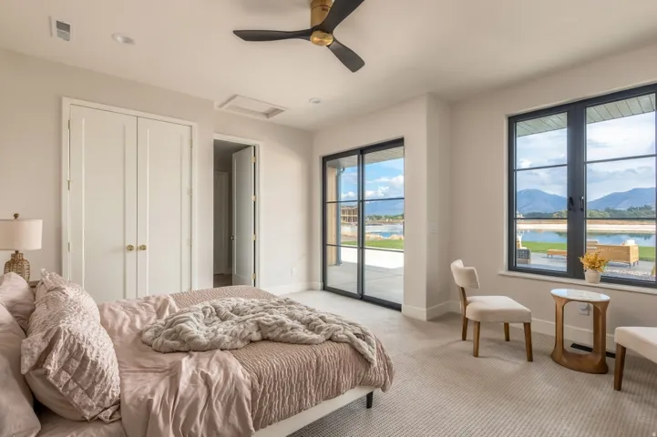 Recessed lighting, ceiling fan, double closet doors with brass hardware, large sliding glass door, and expansive picture windows