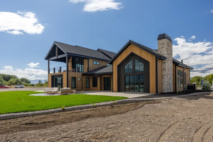 Modern exterior with vertical wood siding, a prominent stone chimney, and a large gabled window feature