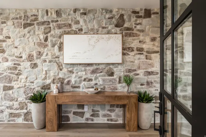 Stone accent wall, wood-finish flooring, and black-framed glass partition