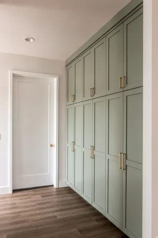 Full-height cabinetry with brass hardware, recessed lighting, and wood-finish flooring