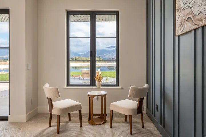 Black-framed window with mountain scenery, vertical paneled accent wall, and light-toned carpeting