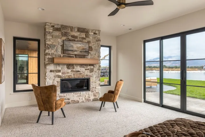 Stone-clad fireplace with wood mantel, built-in electric fireplace, recessed lighting, and a ceiling fan