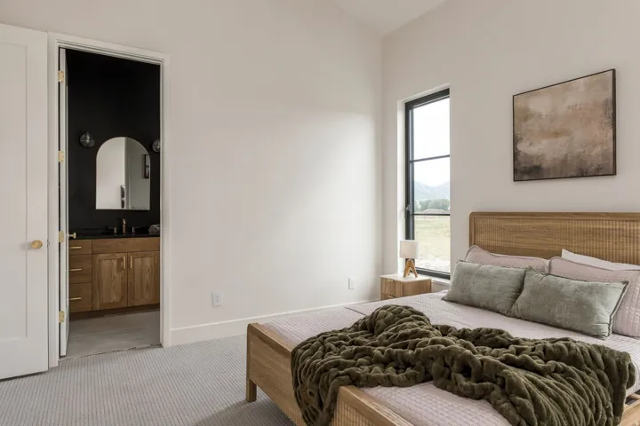 Recessed bedroom lighting with a tall window, light-toned carpet flooring, and a solid wood door with brass hardware